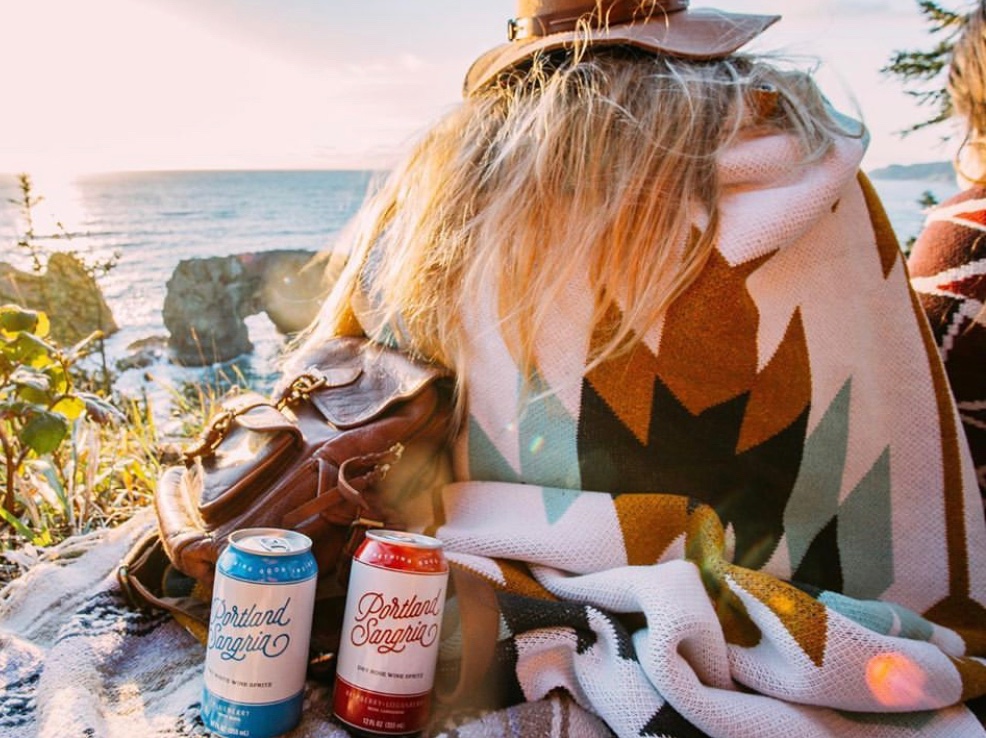 Two cans of Portland Sangria on a blanket at the Oregon coast at golden hour