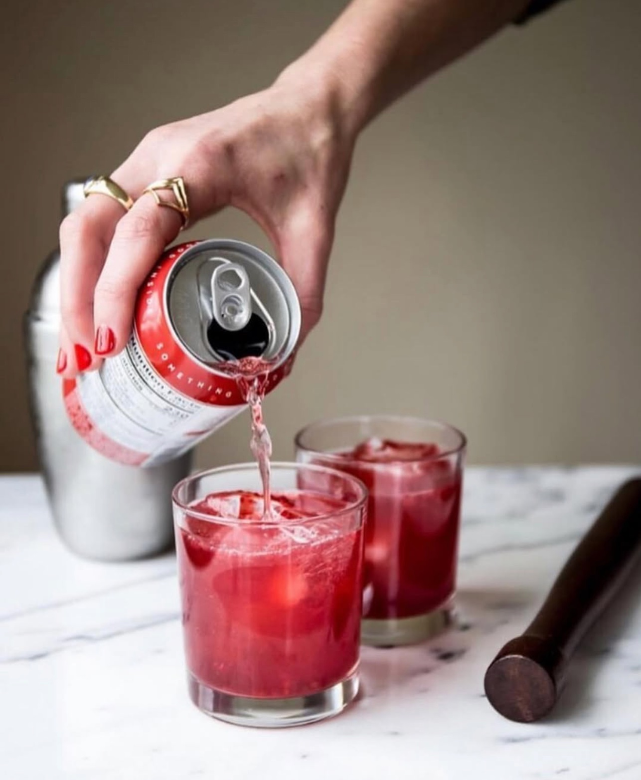 Pouring Raspberry Cardamom sangria over ice in a rocks glass